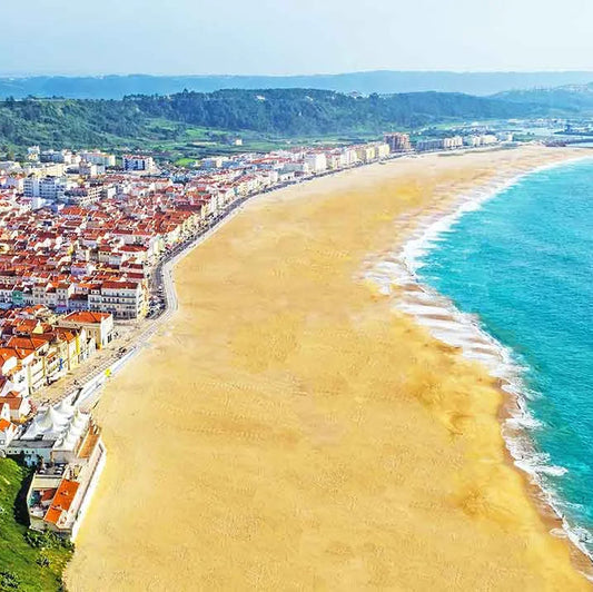Cityscape with a long sandy beach and blue ocean under a clear sky.