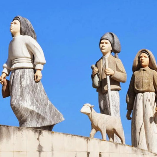Statues of three people with a dog on top of a building against a clear blue sky.