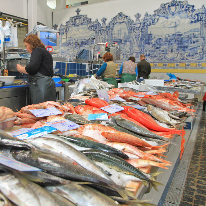 Fish market with fresh fish on display and people shopping.