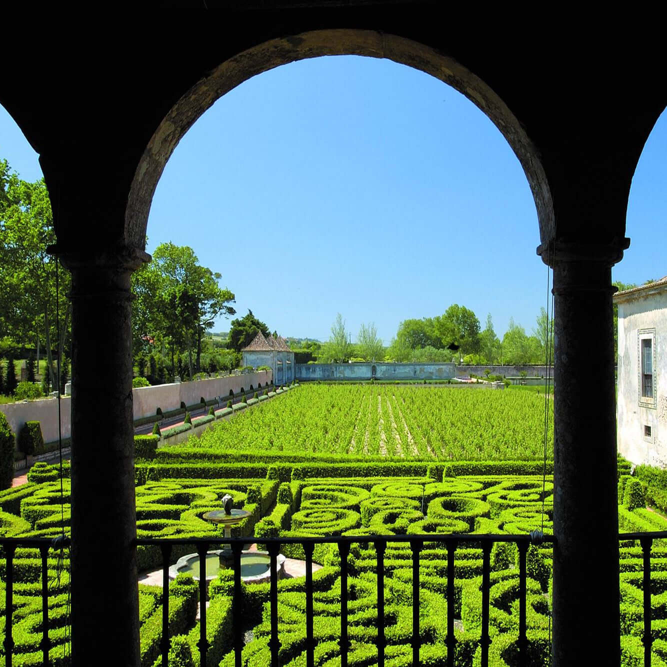 View of a garden from behind arches with a building in the background